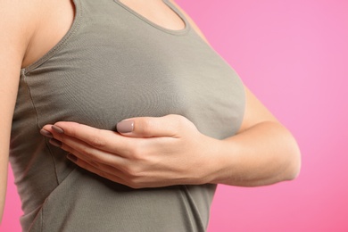 Photo of Woman checking her breast on color background, closeup