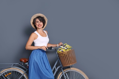 Portrait of beautiful young woman with bicycle on color background