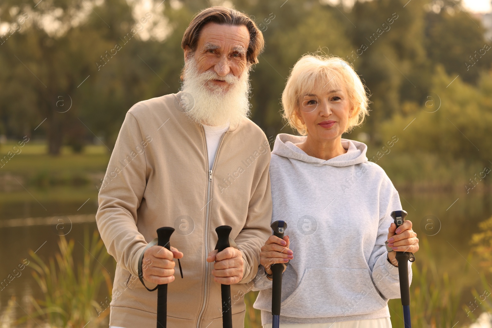 Photo of Senior man and woman with Nordic walking poles outdoors