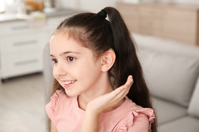 Little girl with hearing aid at home