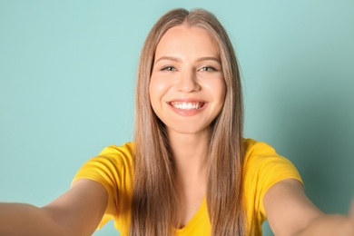 Photo of Young beautiful woman taking selfie against color background