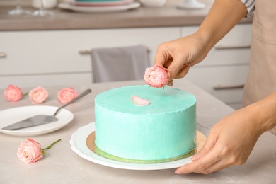 Photo of Woman decorating fresh delicious birthday cake in kitchen, closeup