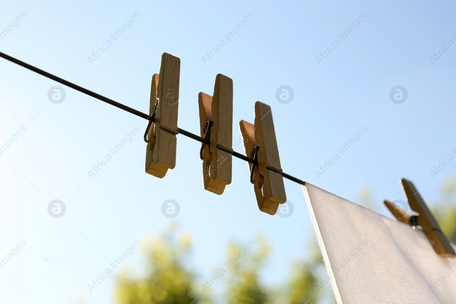 Photo of Wooden clothespins hanging on washing line outdoors