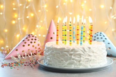 Delicious birthday cake with burning candles on table