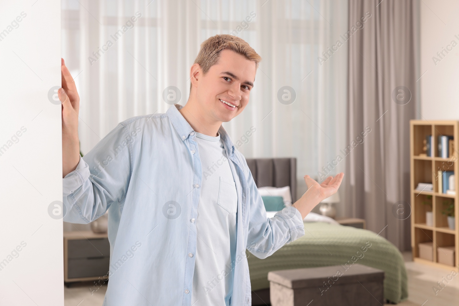 Photo of Happy man inviting to come in room