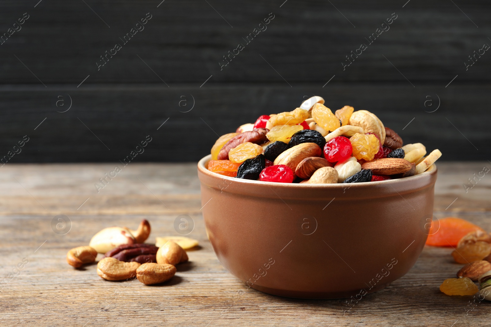 Photo of Bowl with different dried fruits and nuts on table. Space for text