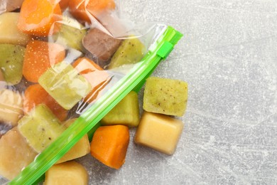 Different frozen fruit puree cubes in plastic bag on table, flat lay. Space for text