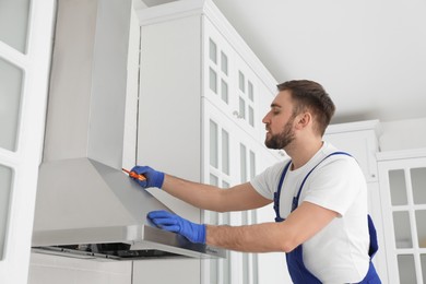 Worker repairing modern cooker hood in kitchen