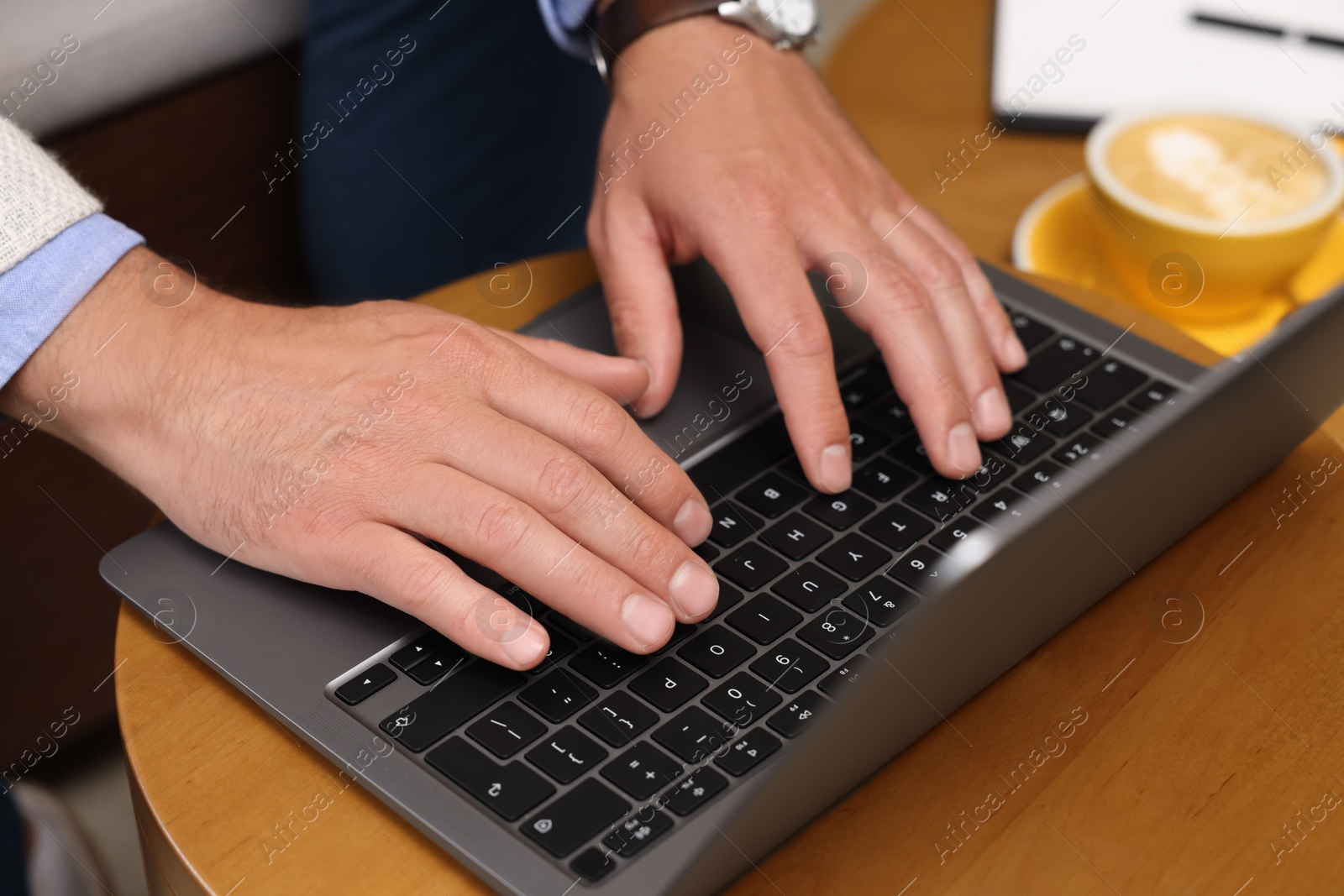 Photo of Man using laptop at wooden table, closeup