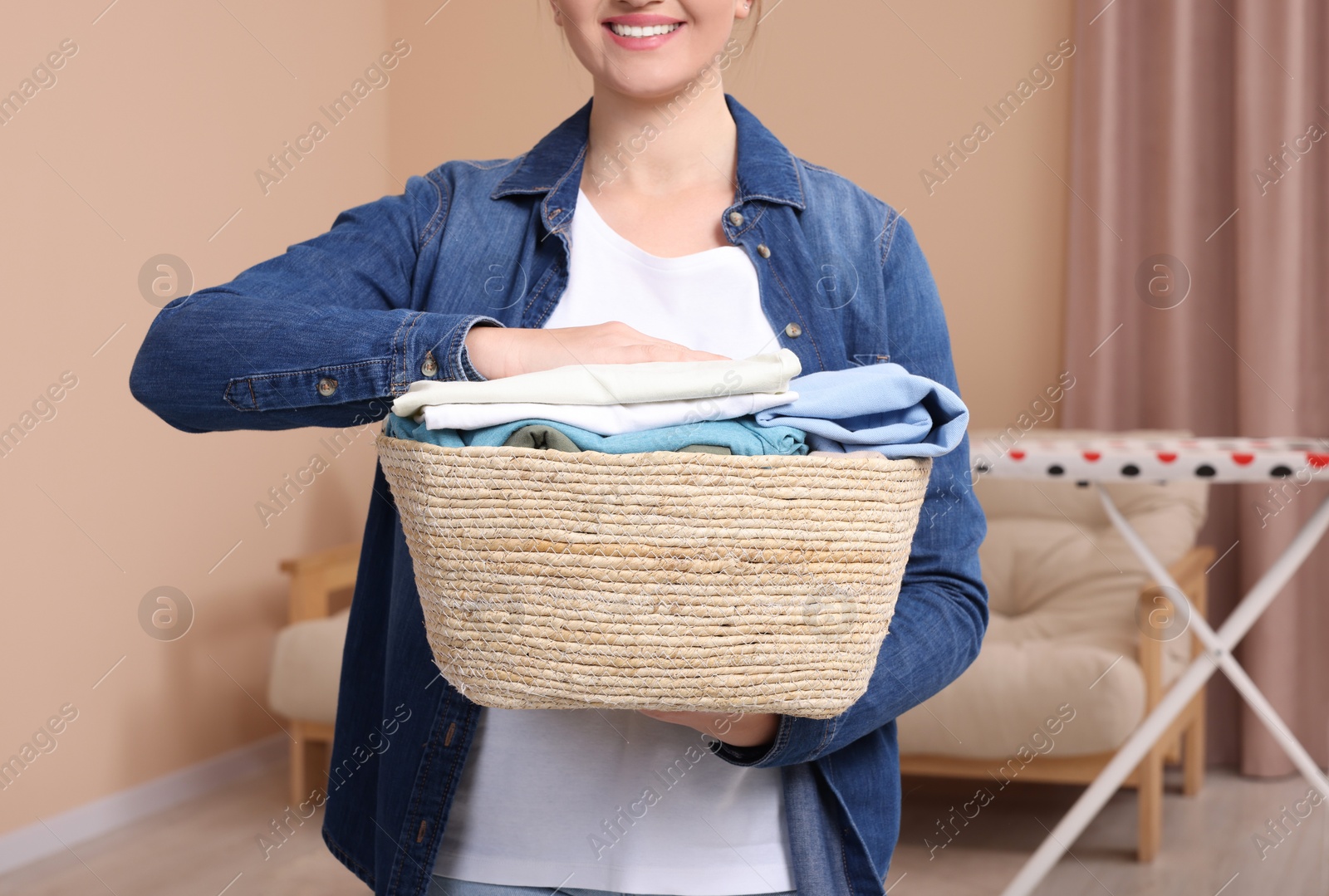 Photo of Happy woman with basket full of laundry at home, closeup