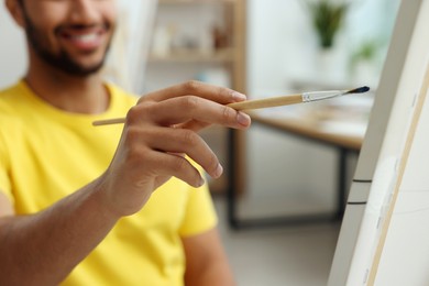 Photo of Young man painting in studio, selective focus. Creative hobby