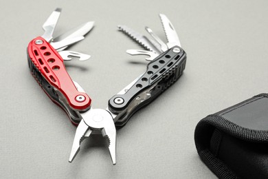 Compact portable multitool and case on light grey background, closeup