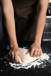 Photo of Woman kneading dough for pastry on table