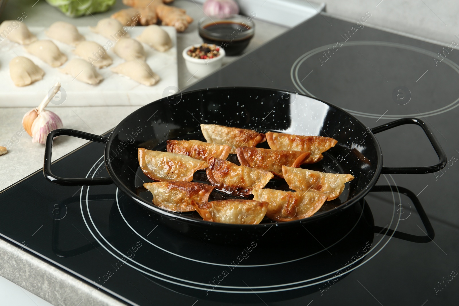 Photo of Cooking gyoza on frying pan with hot oil in kitchen
