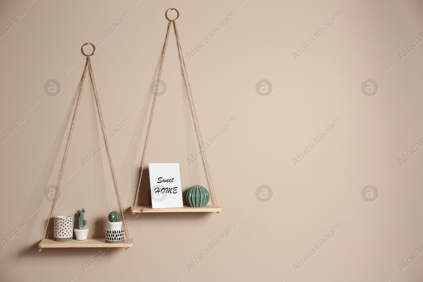 Photo of Wooden shelves with different decorative elements on beige wall, space for text