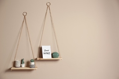 Photo of Wooden shelves with different decorative elements on beige wall, space for text