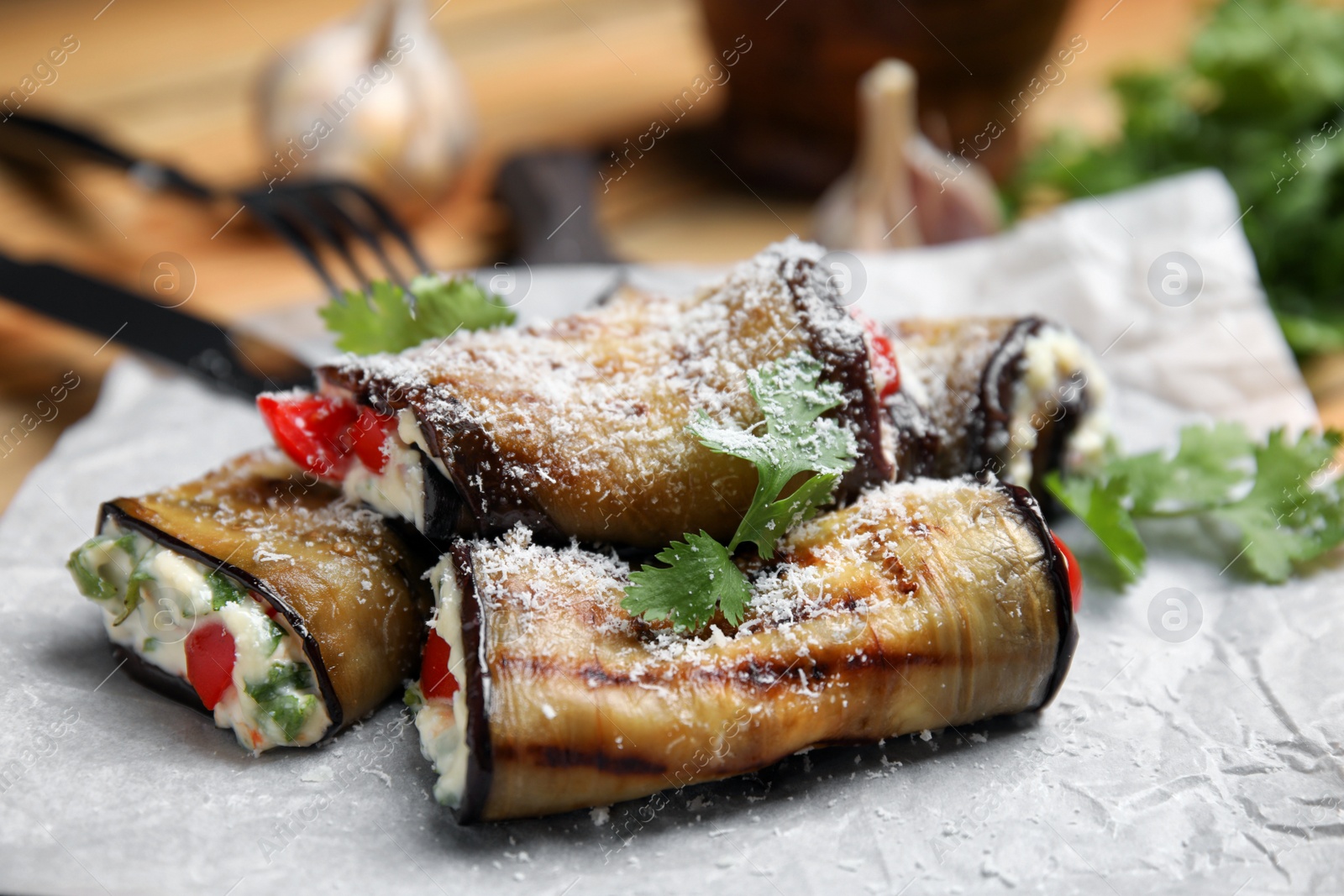 Photo of Delicious fried eggplant rolls with cheese, tomatoes and parsley on paper, closeup