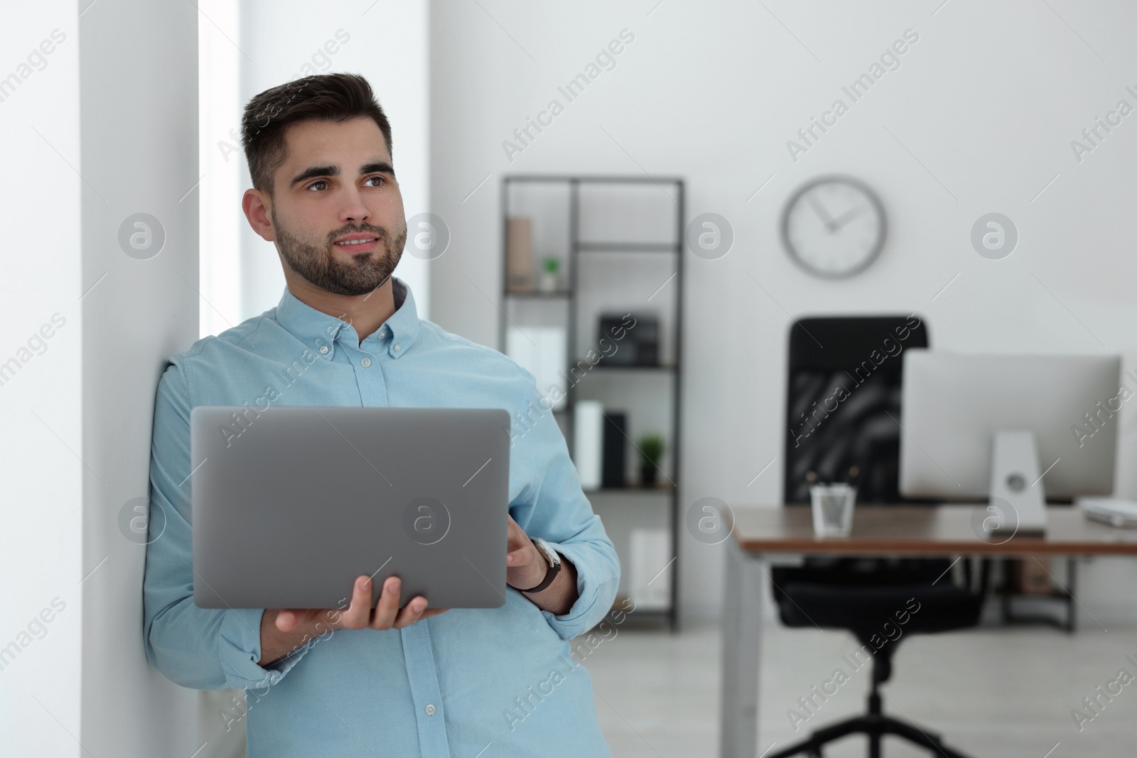 Photo of Happy young programmer with laptop in office