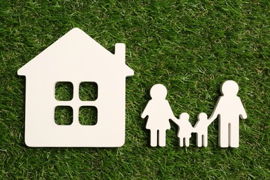 Photo of Family and house figures on green grass, flat lay