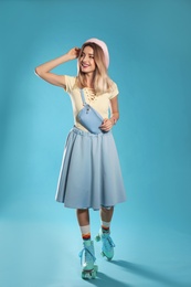 Photo of Young woman with retro roller skates on color background