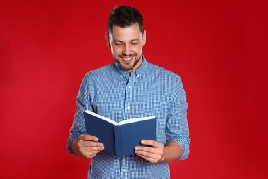 Handsome man reading book on red background