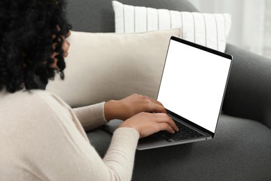 Woman using laptop on sofa at home, closeup