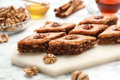 Photo of Delicious honey baklava with walnuts on served white marble table, closeup