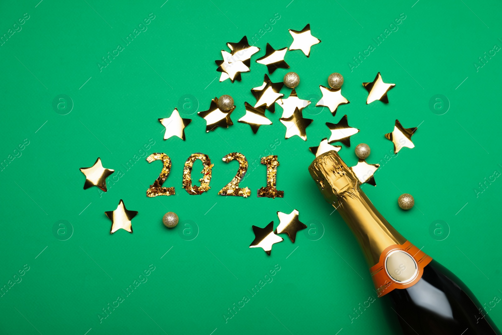 Photo of Flat lay composition with confetti and bottle of champagne on green background. New Year celebration