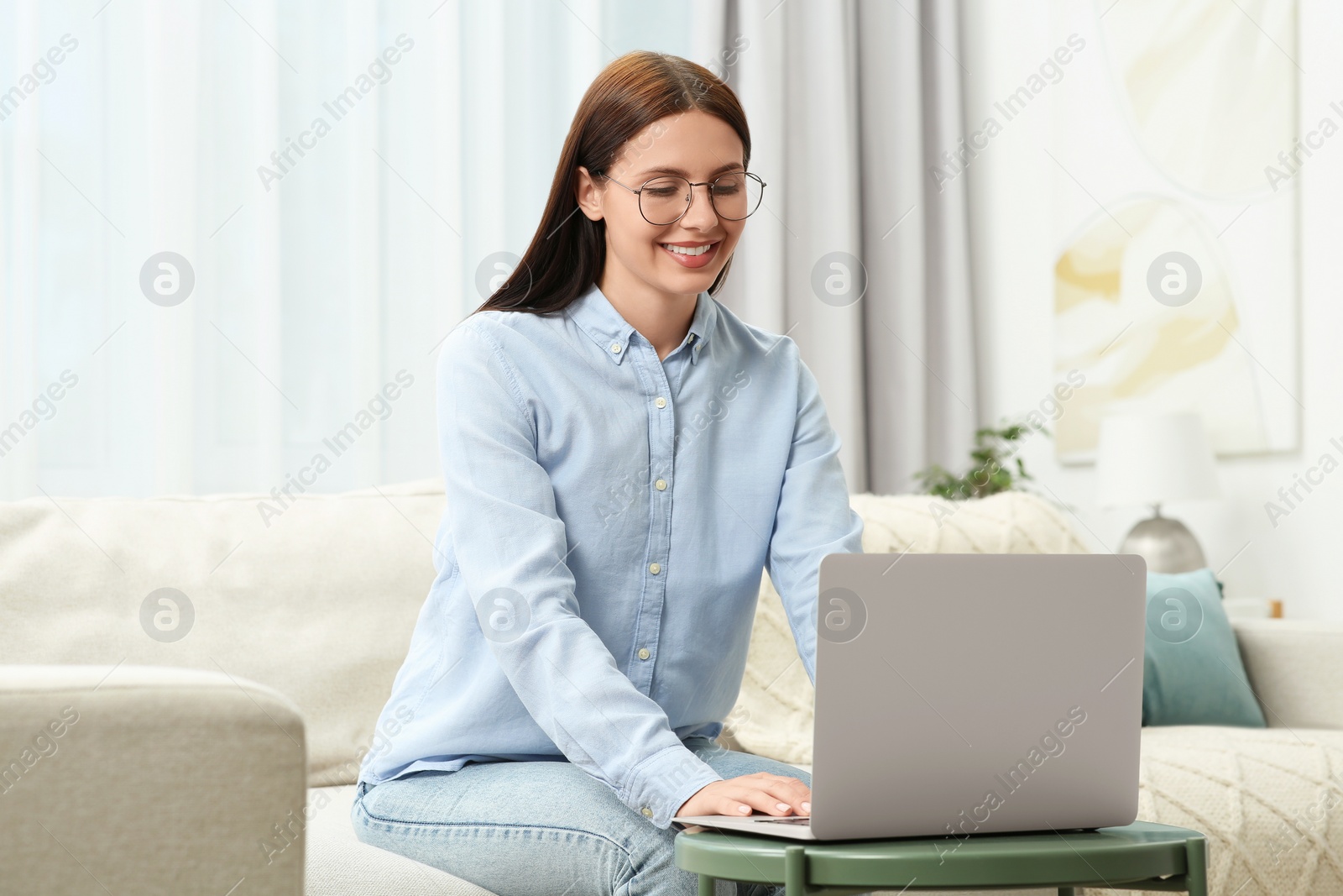 Photo of Smiling woman in stylish eyeglasses working with laptop at home