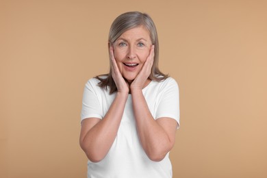 Photo of Portrait of surprised senior woman on beige background