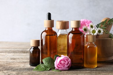 Photo of Aromatherapy. Different essential oils, flowers, mortar and pestle on wooden table