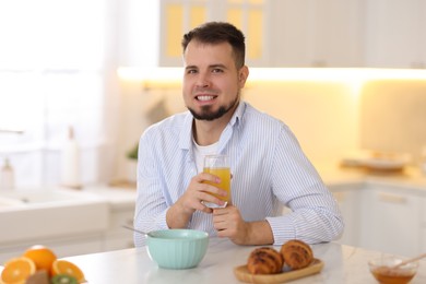Smiling man eating tasty cornflakes at breakfast indoors