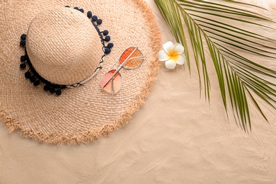 Photo of Flat lay composition with stylish hat, flower and tropical leaf on sand