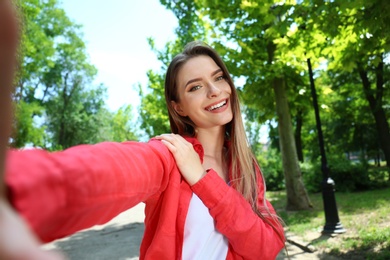Happy young woman taking selfie in park