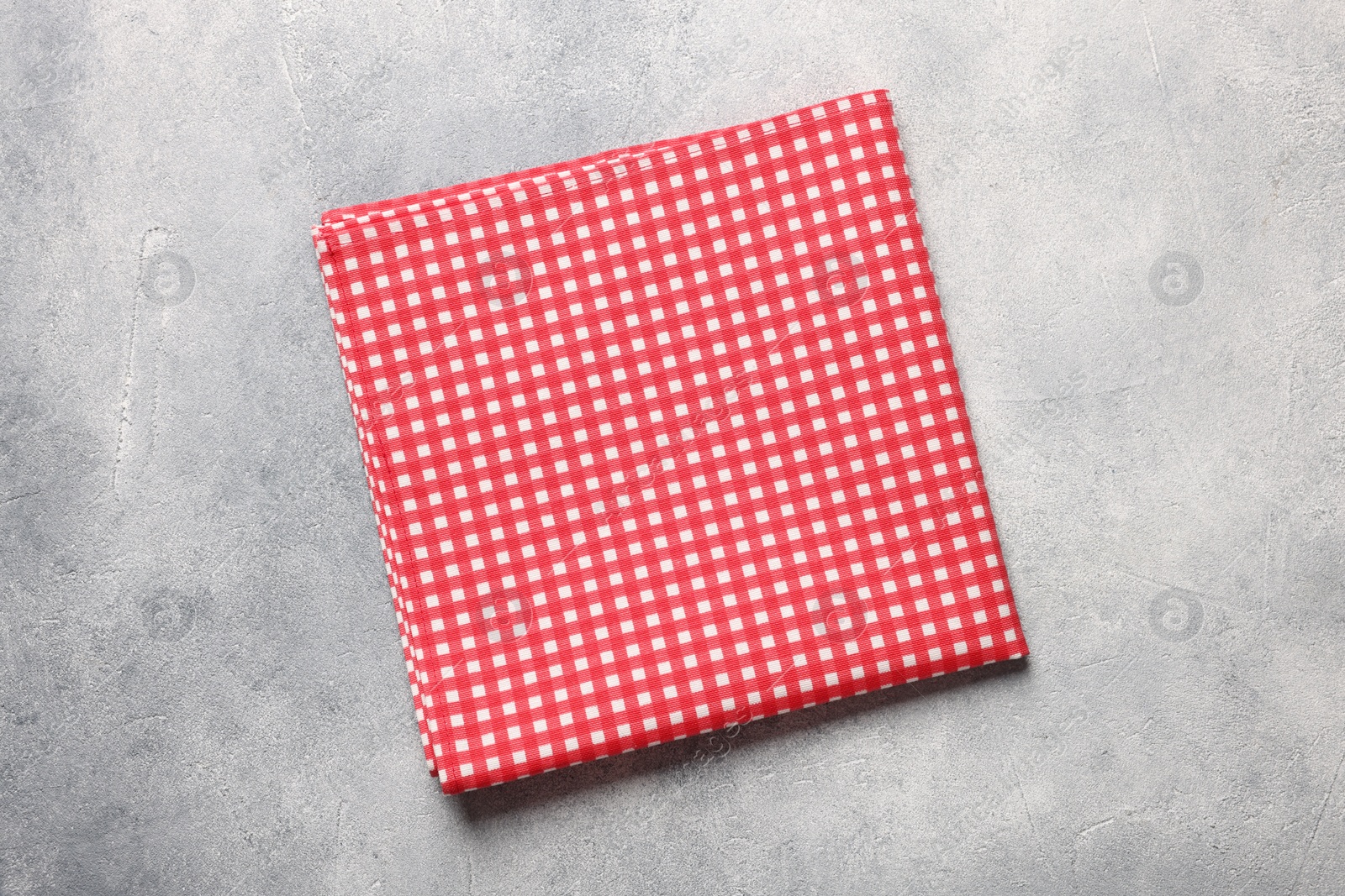 Photo of Red checkered tablecloth on light gray textured table, top view