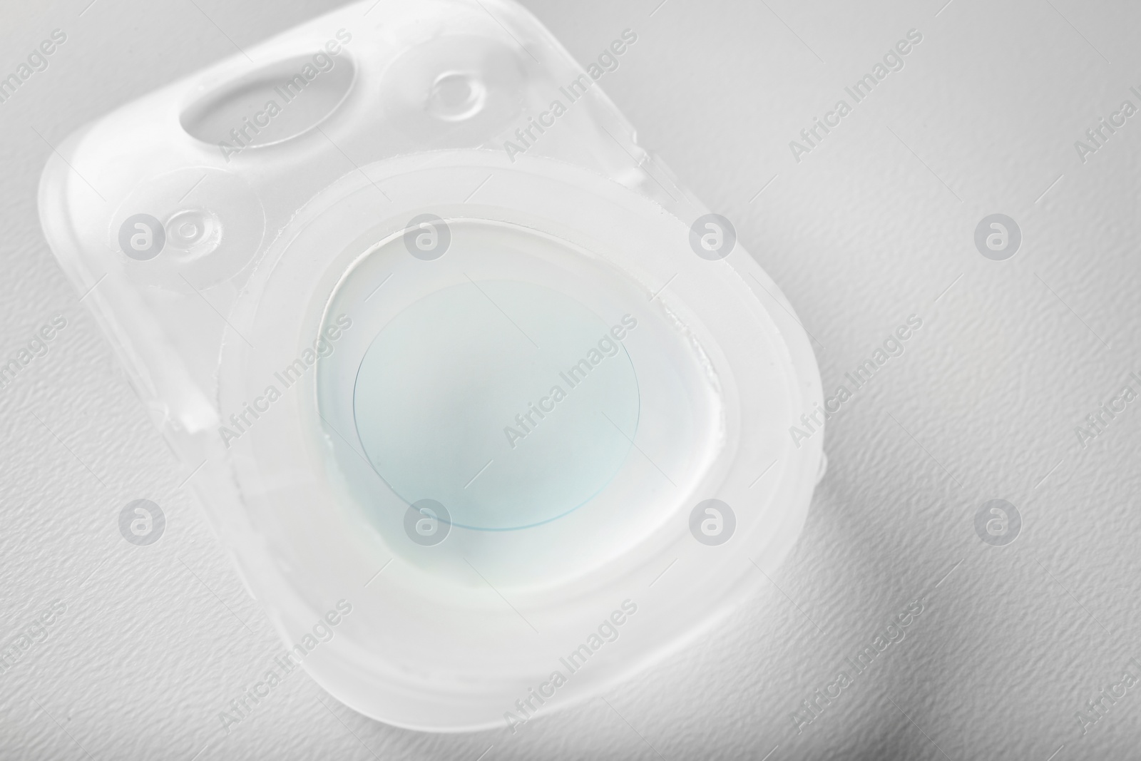 Photo of Container with contact lens on white table, closeup