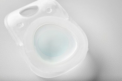 Container with contact lens on white table, closeup