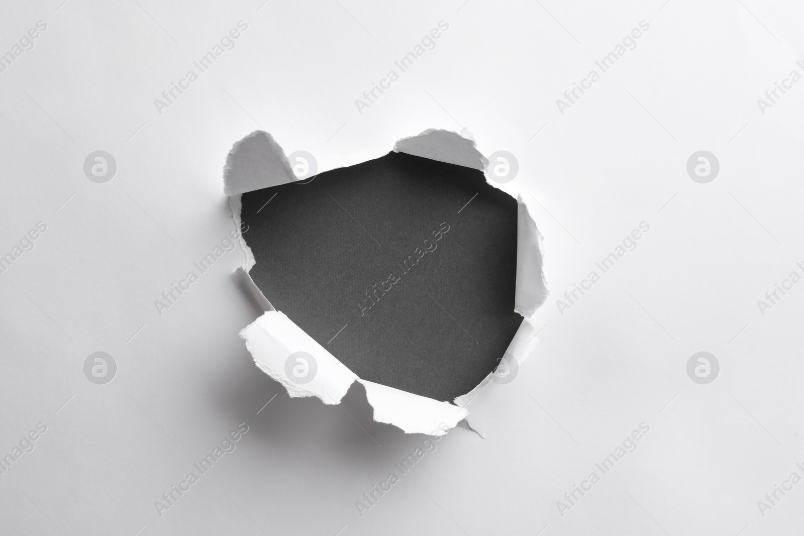 Photo of Hole in white paper on black background