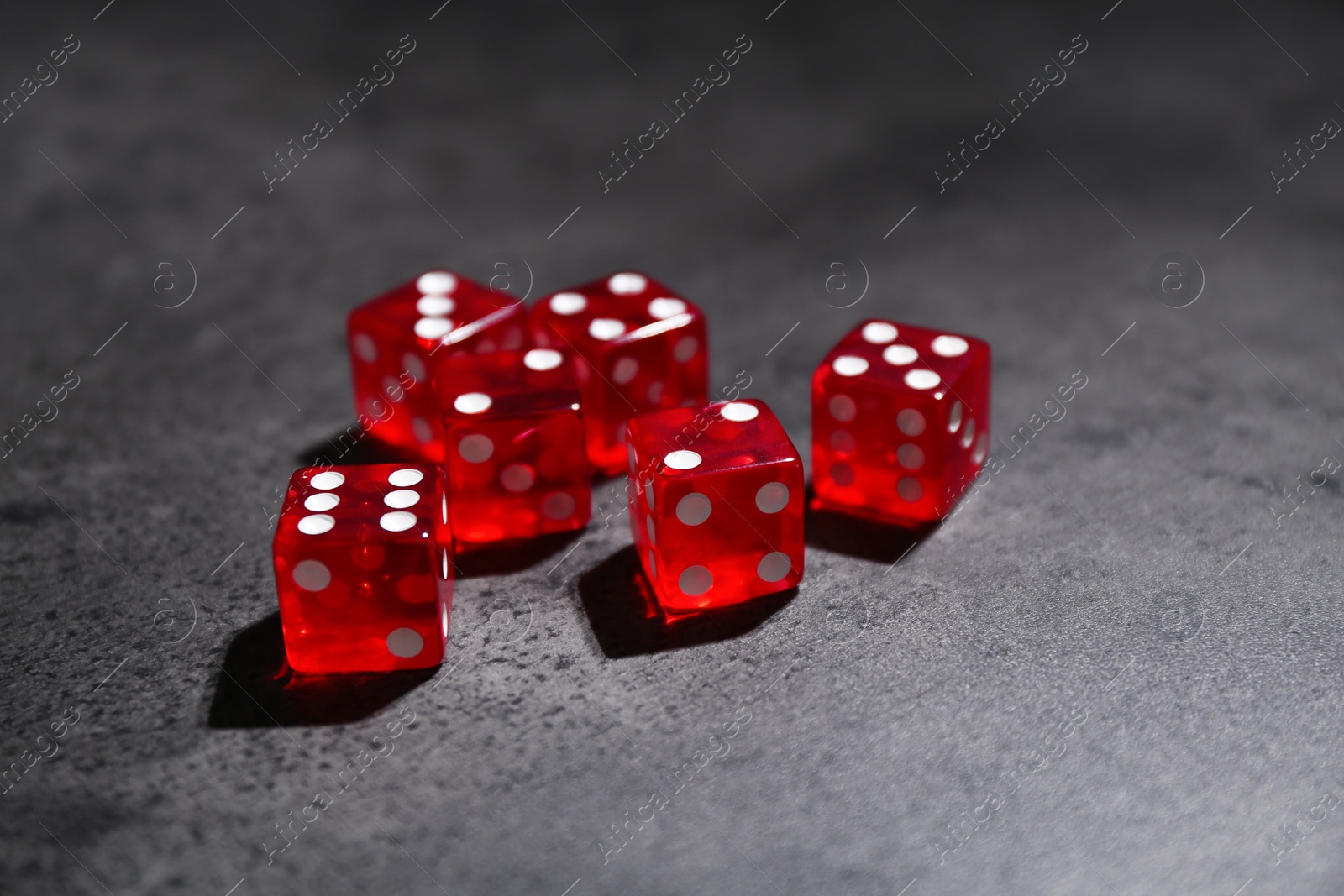 Photo of Many red game dices on grey textured table