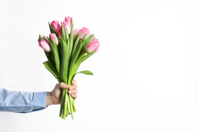 Photo of Man holding bouquet of beautiful spring tulips on light background, closeup. International Women's Day