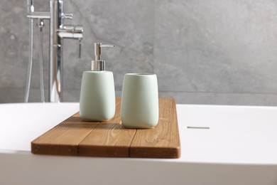 Photo of Set of bath accessories on tub in bathroom, space for text