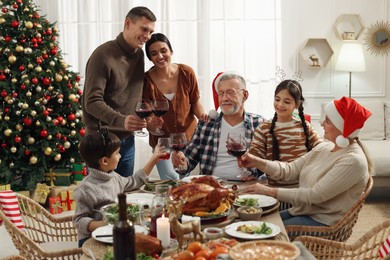 Happy family clinking glasses of drinks at festive dinner indoors. Christmas celebration