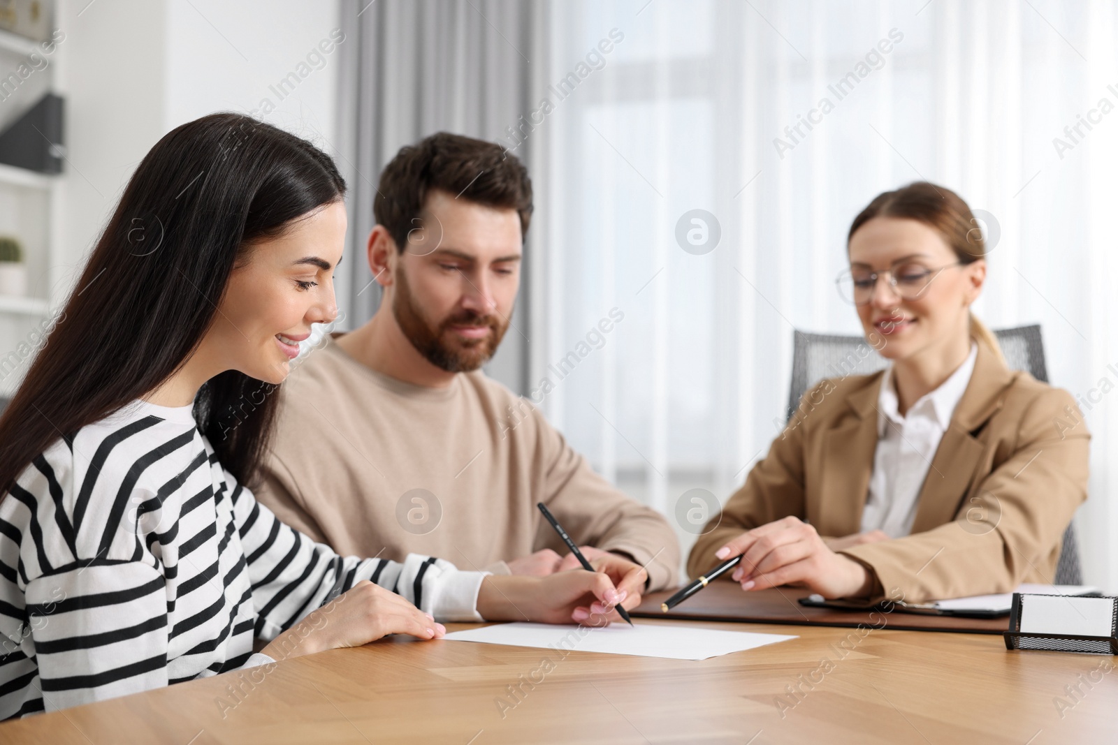 Photo of Couple signing document while having meeting with lawyer in office, selective focus