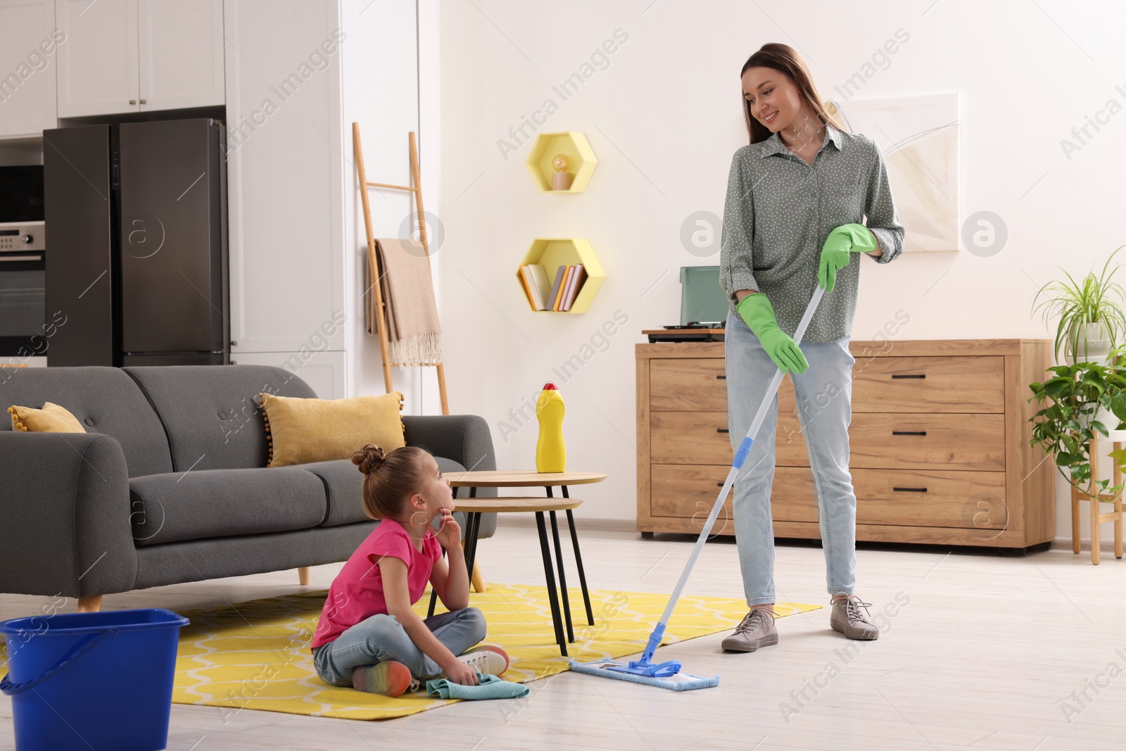 Photo of Spring cleaning. Mother and daughter tidying up living room together