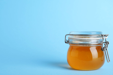 Photo of Jar of organic honey on light blue background. Space for text