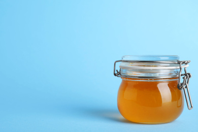 Jar of organic honey on light blue background. Space for text