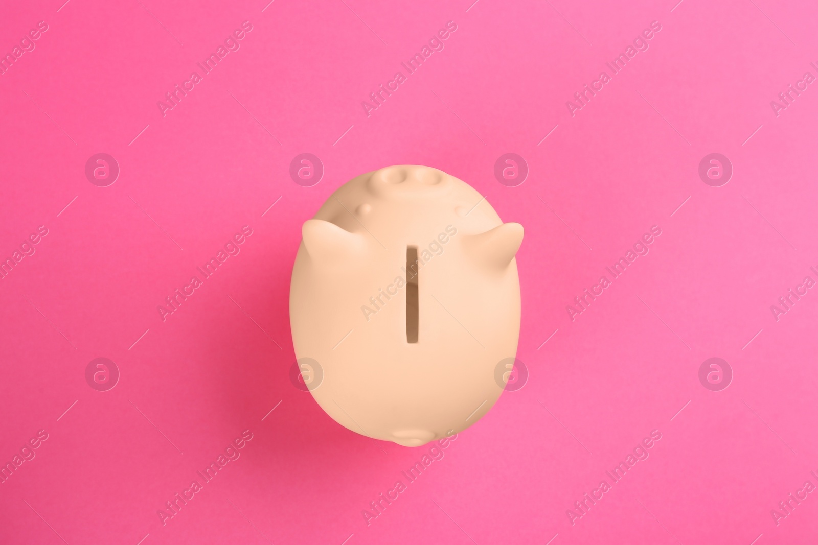 Photo of Beige piggy bank on pink background, top view