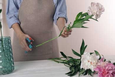 Photo of Florist cutting flower stem with pruner at workplace, closeup
