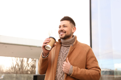 Photo of Man with cup of coffee on city street in morning
