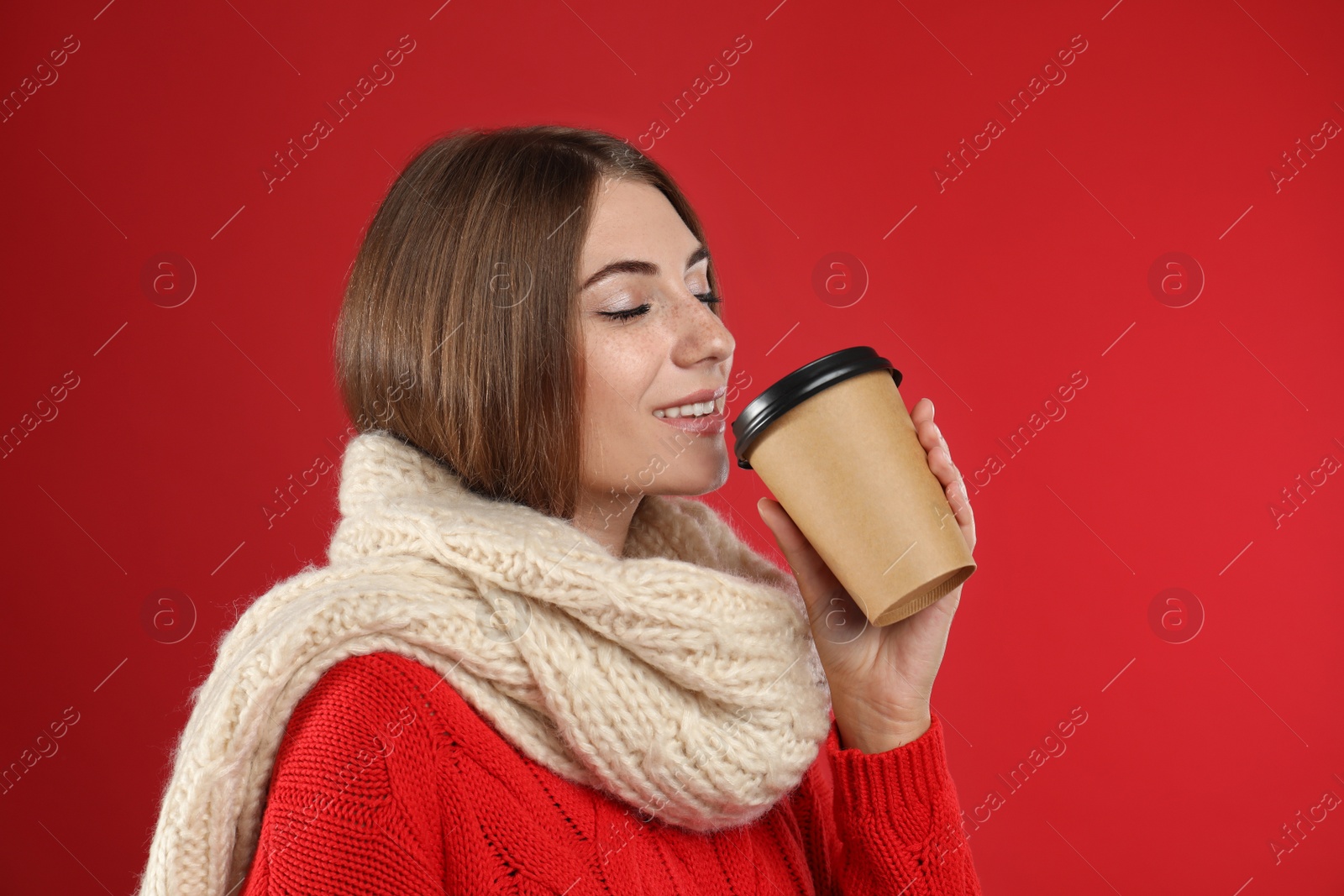 Photo of Happy beautiful woman with paper cup of mulled wine on red background